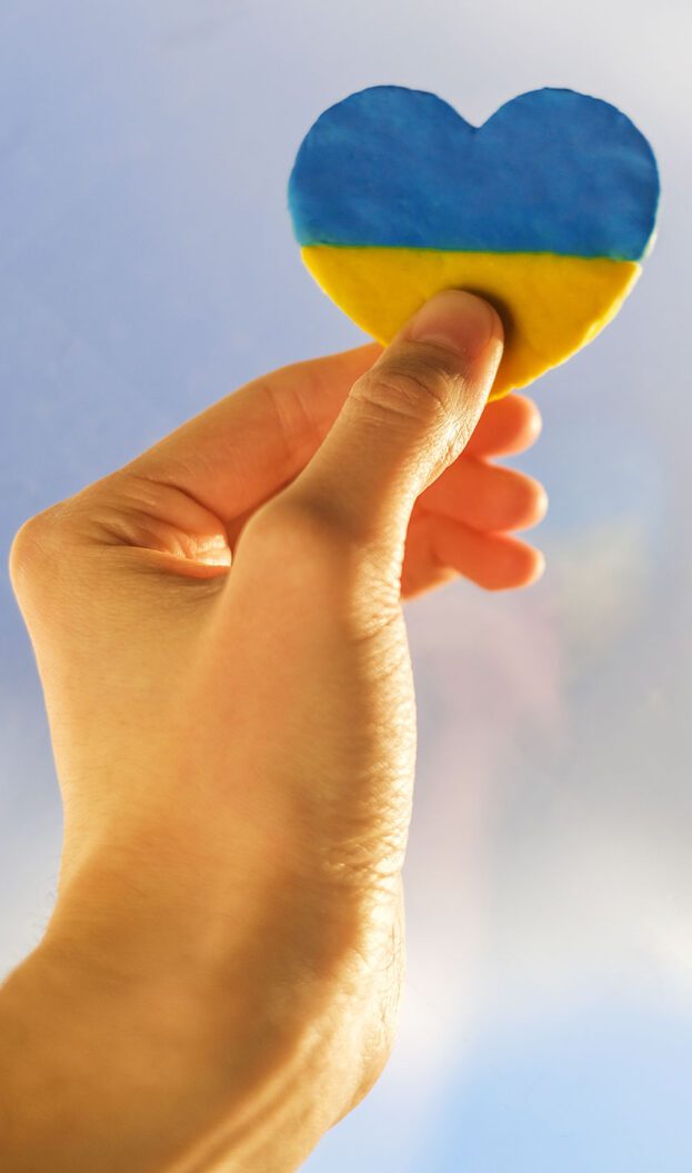 Hand holding a blue and yellow heart, the colors of Ukraine